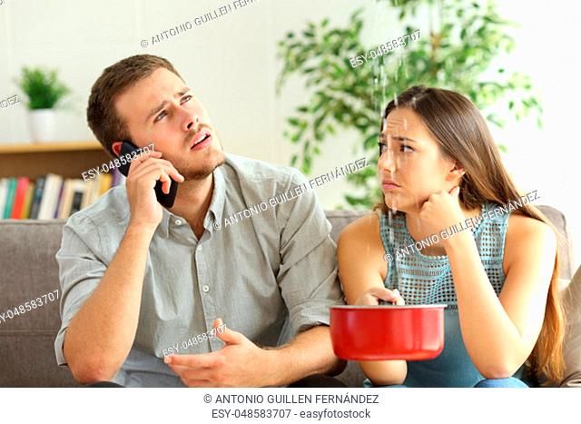 Desperate couple callling to insurance worried about home leaks in the living room