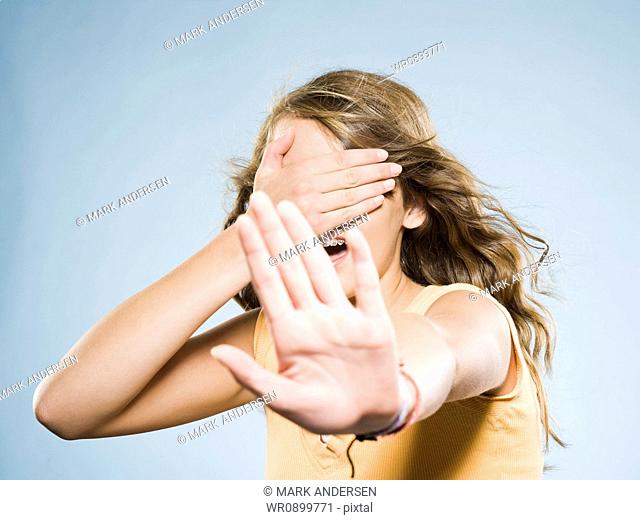 Girl covering eyes and holding out hand
