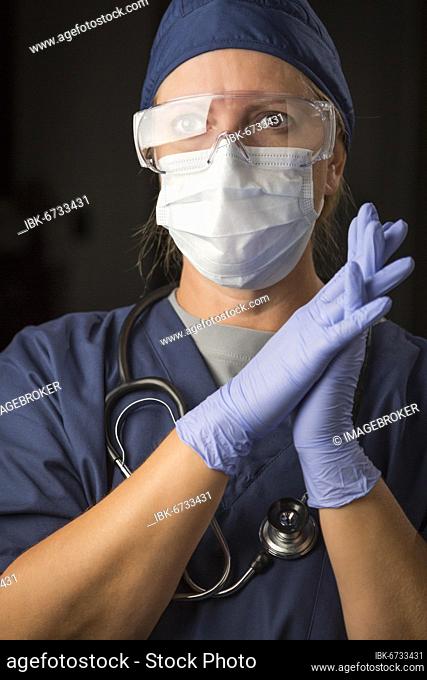 Concerned female doctor or nurse wearing protective facial wear and surgical gloves