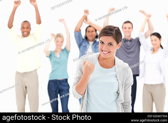 Woman clenching her fist with people behind raising their arms