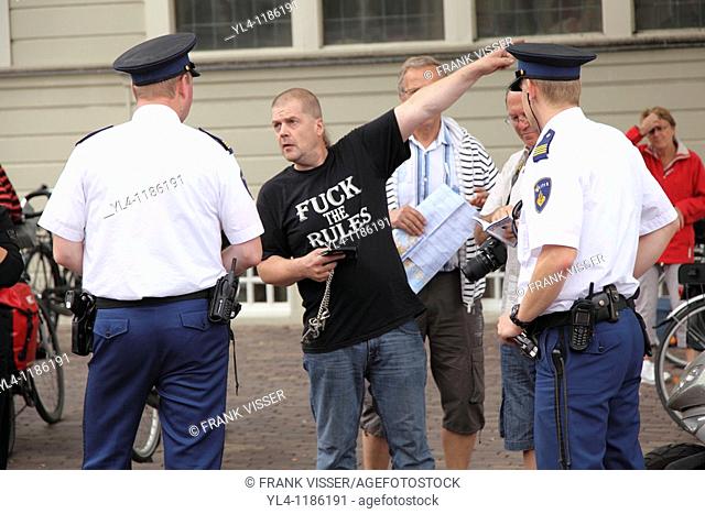 Tourists are talking to policemen. The text on the T-shirt of one of them makes it a humorous streetscene. Amsterdam, The Netherlands