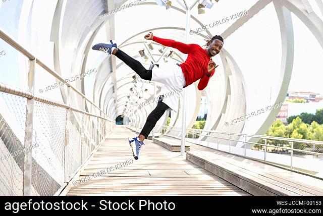 Male sportsman smiling while jumping on walkway