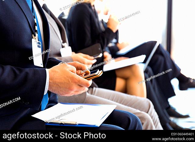 Business men using mobile phones sitting at training room, conference hall