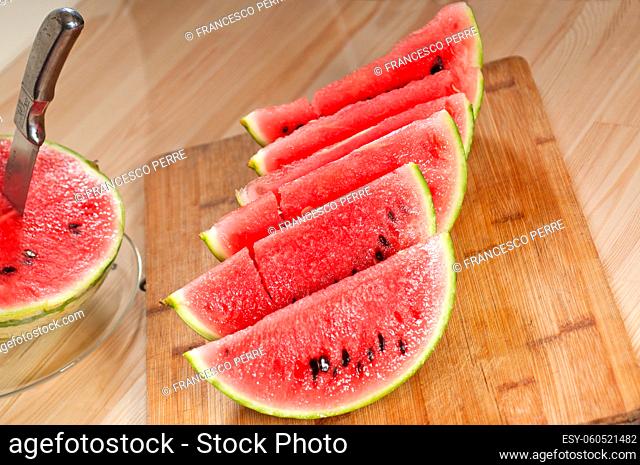 fresh ripe watermelon sliced on a wood table with knife
