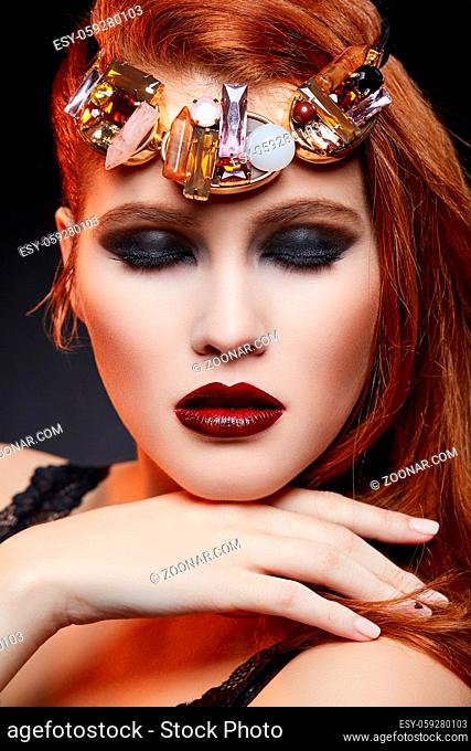 beautiful young woman with dark lips and smokey eye makeup. Long red hair. Studio beauty shot. Copy space