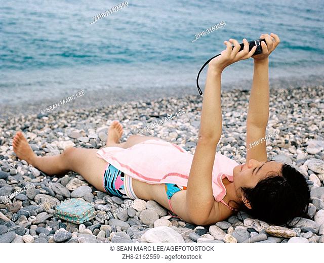 A girl takes a self portrait of herself on a rocky beach at Chi Shing Tan beach in Hualien, Taiwan