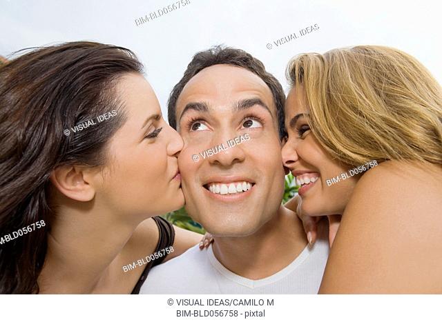 Hispanic women kissing man on cheeks