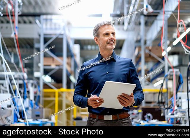 Mature businessman holding digital tablet in factory
