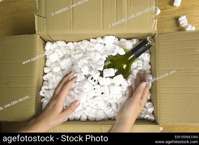 Wine bottle in fragile delivery package top view, opened mail with champange bottle, service, delivery, transport, alcohol concept closeup