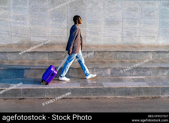 Smiling businessman with suitcase walking on step