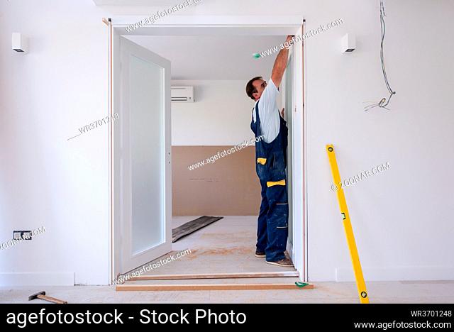 male workers carpenters installing interior glass door with a wooden frame at new luxury apartment