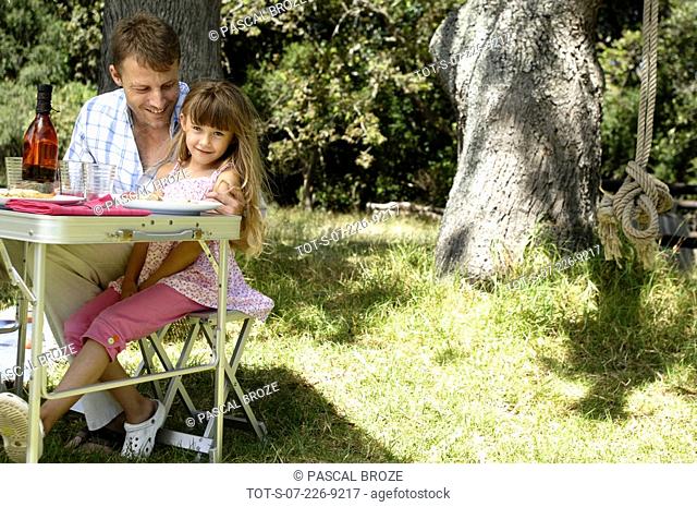 Portrait of a girl sitting with her father at a picnic table