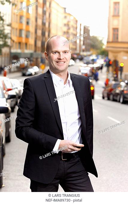 Man standing through city street, smiling, portrait