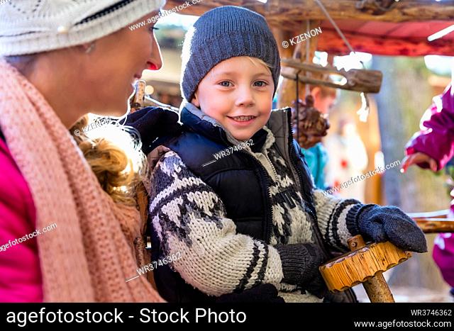 Mother with son and carousel on traditional Christmas market