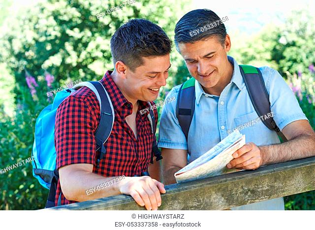 Father With Adult Son Looking At Map On Hike In Countryside Together