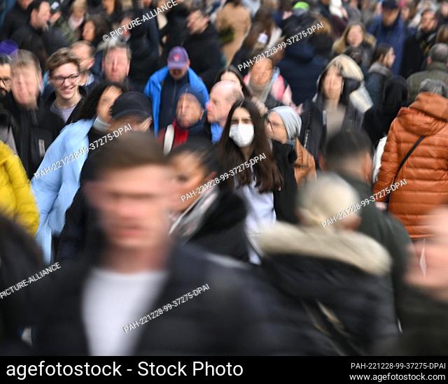 28 December 2022, Hessen, Frankfurt/Main: A woman wearing a mask walks in the crowd along Frankfurt's shopping mile Zeil (shot with longer shutter speed)