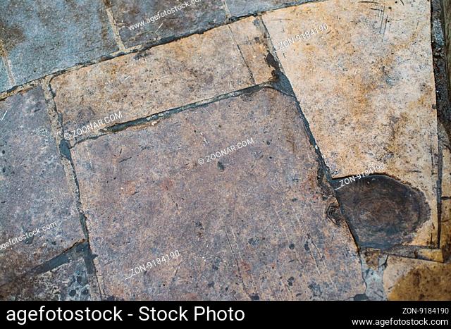Rough stone tile floor with cracks and small stones abstract background texture