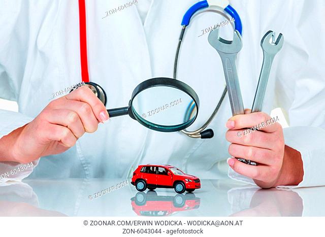 Ein Modell eines Autos wird von einem Arzt untersucht. Symbolfoto für Werkstatt, Service und Autokauf