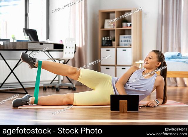 teenage girl with tablet pc exercising at home