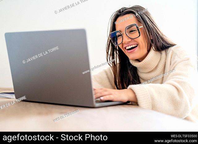 Happy young freelancer using laptop at desk in home office
