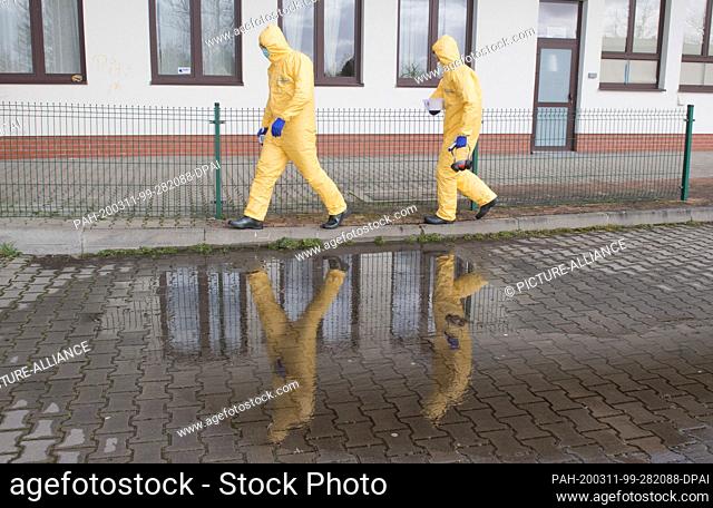 11 March 2020, Poland, Swinoujscie: Two members of the Polish rescue service go to the Garz border crossing in Swinoujscie in Poland to check a coach on the...