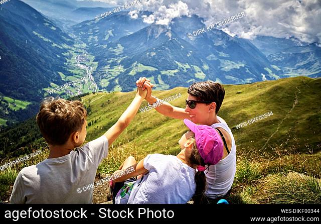 Happy mother with two children having a break from hiking in alpine scenery, Passeier Valley, South Tyrol, Italy