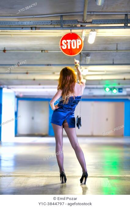 Attractive woman and STOP sign in empty underground parking-lot
