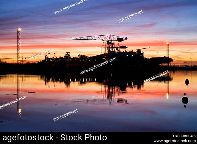 Spectucalar sunrise above a shipyard on the banks of the Dutch river merwede