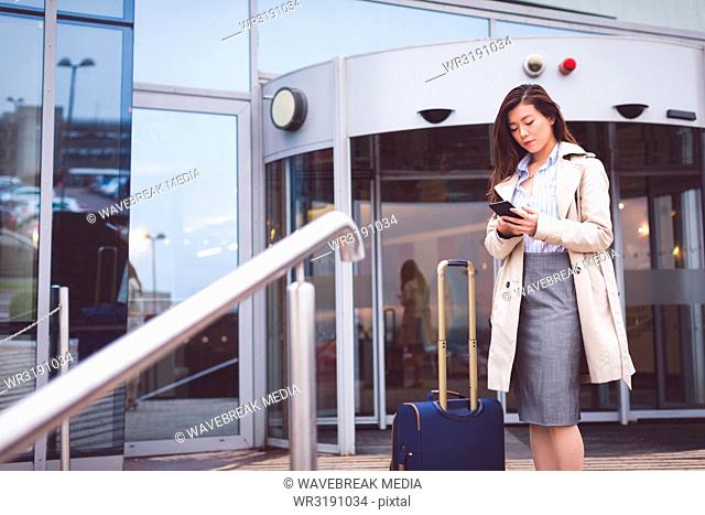 Businesswoman using mobile phone outside a hotel