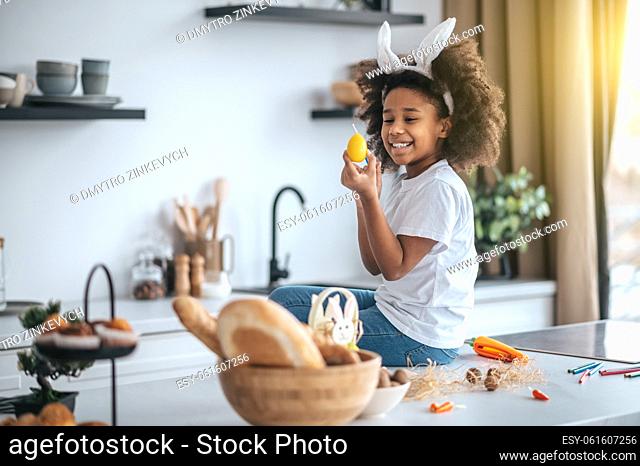 Easter bunny. Cute girl wuth bunny ears in the kitchen smiling happily