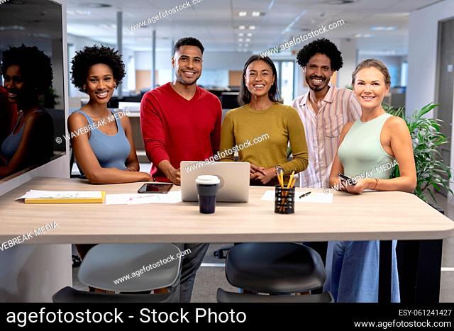 Team of happy male and female biracial advisors with laptop at desk during meeting in workplace