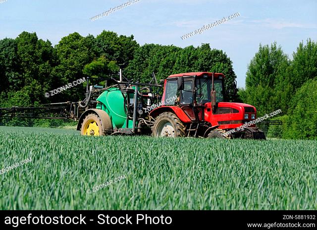 farm machinery tractor with long black sprayer working in field