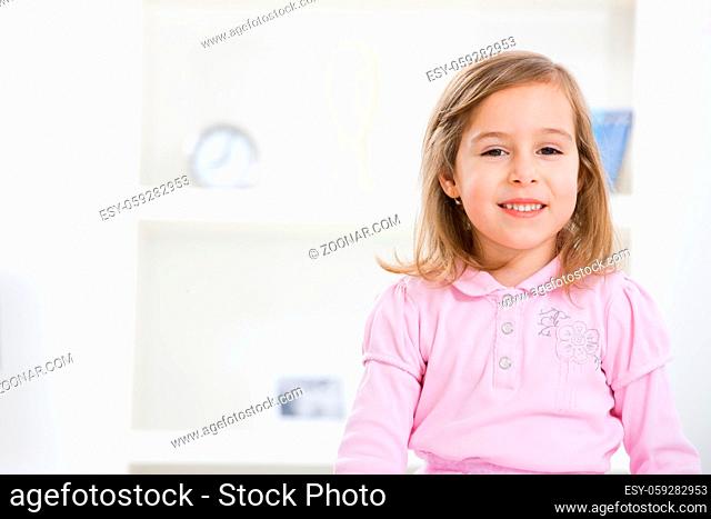 Portrait of cute little girl wearing pink dress, smiling