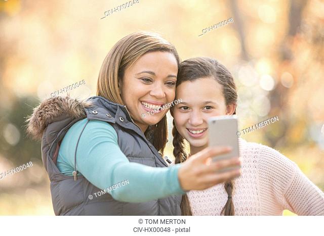 Mother and daughter taking selfie with camera phone outdoors