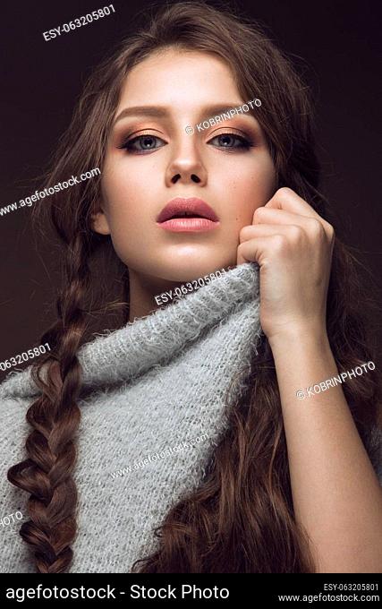 Beautiful young girl with gentle make-up in warm sweater and long straight hair. Beauty face. Studio portrait
