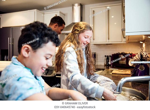 Little girl and her younger brother are doing the dishes after breakfast at home