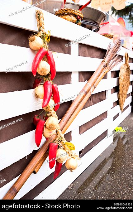 Garlic and hot chili peppers hanging on white wooden background outdoor