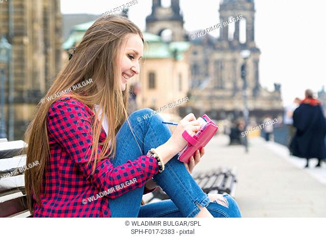 MODEL RELEASED. Young woman making notes in notebook, Dresden, Germany