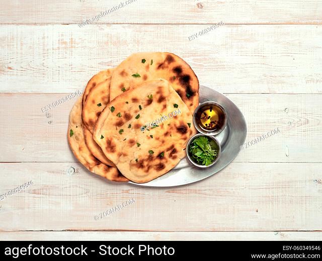 Fresh naan bread on white wooden background with copy space. Top view of several perfect naan flatbreads on metal tray
