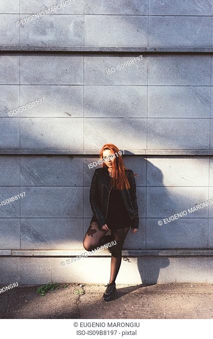 Portrait of red haired woman leaning against wall