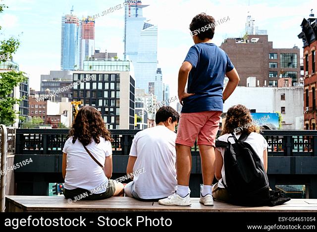 Four young people sitting in Observatory point in High Line against skyline of New York City