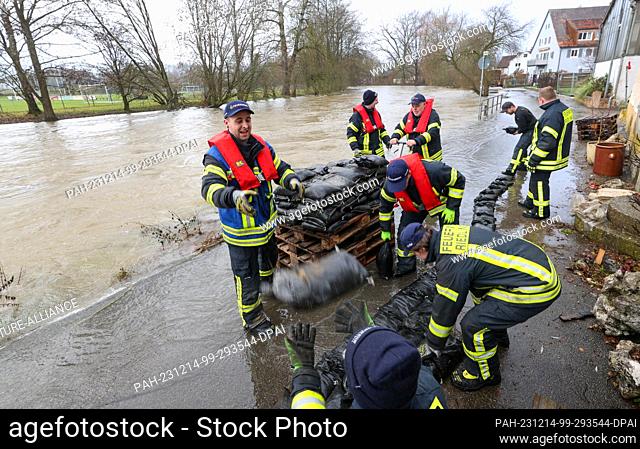 14 December 2023, Baden-Württemberg, Riedlingen: Firefighters use sandbags to build a dam on the Danube to protect houses in Riedlingen from flooding