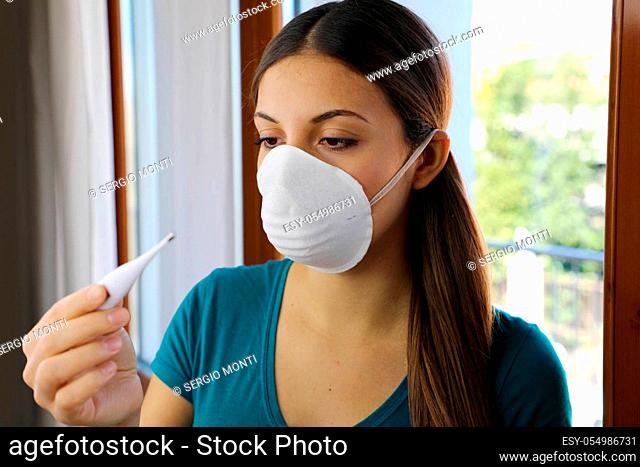 COVID-19 Pandemic Coronavirus Mask Fever Worry Woman Checking Temperature with Thermometer at Home Symptom of SARS-CoV-2