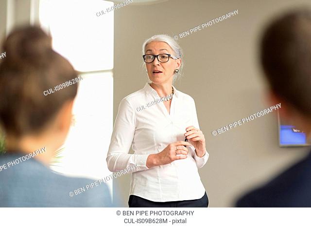 Over shoulder view of mature businesswoman giving office presentation