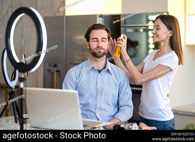 Appearance. Long-haired woman making hair to a man before webinar