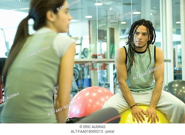 Two young adults sitting on fitness balls