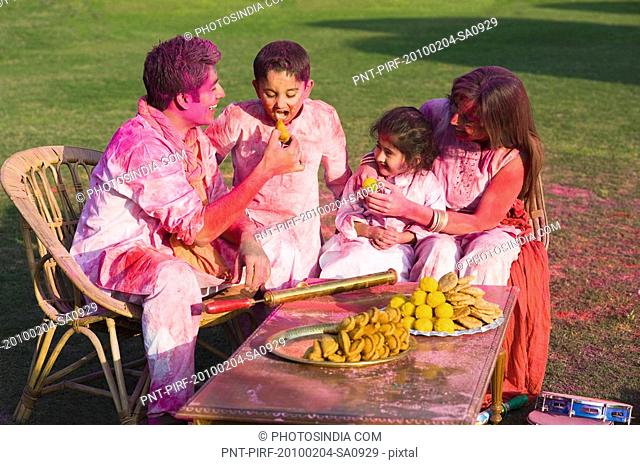 Family celebrating Holi with traditional Indian cuisines