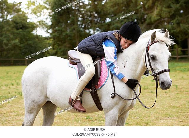 Girl cuddling her pony