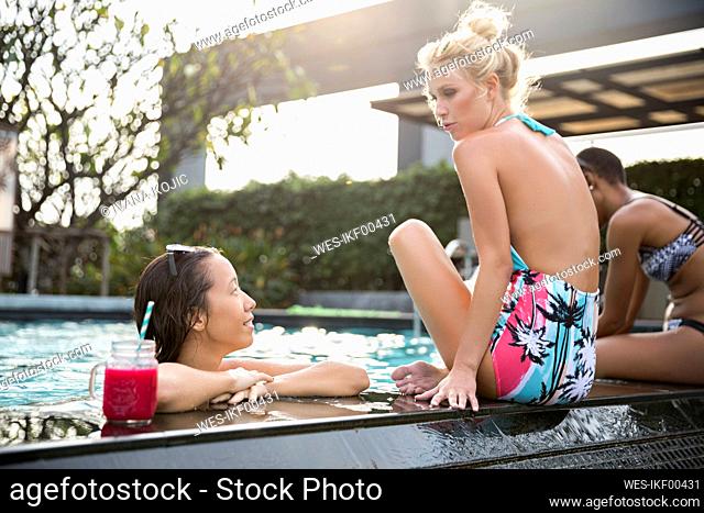 Woman talking to friend in swimming pool at resort