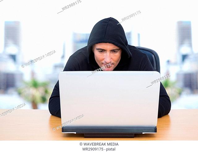 Criminal in hood on laptop by windows